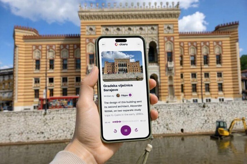A hand holding a smartphone displaying information about Gradska vijecnica in Sarajevo. 1