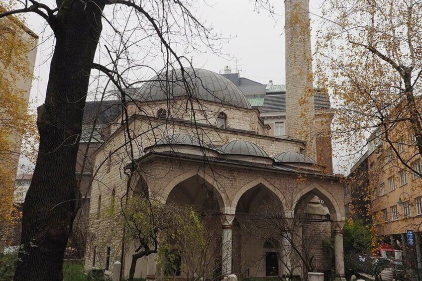 A historic building with arches and a dome, surrounded by trees and urban buildings. 4