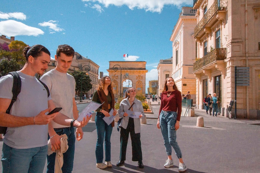 A group of people standing on a city street with historic architecture and a clear sky. 2