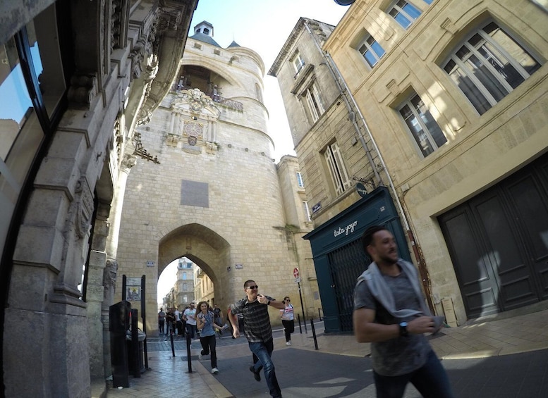 A historic stone archway with a clock, surrounded by buildings and pedestrians. 5