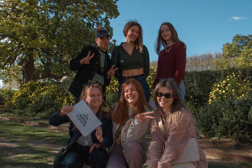 A group of people posing in a park with trees and yellow flowers in the background. 3