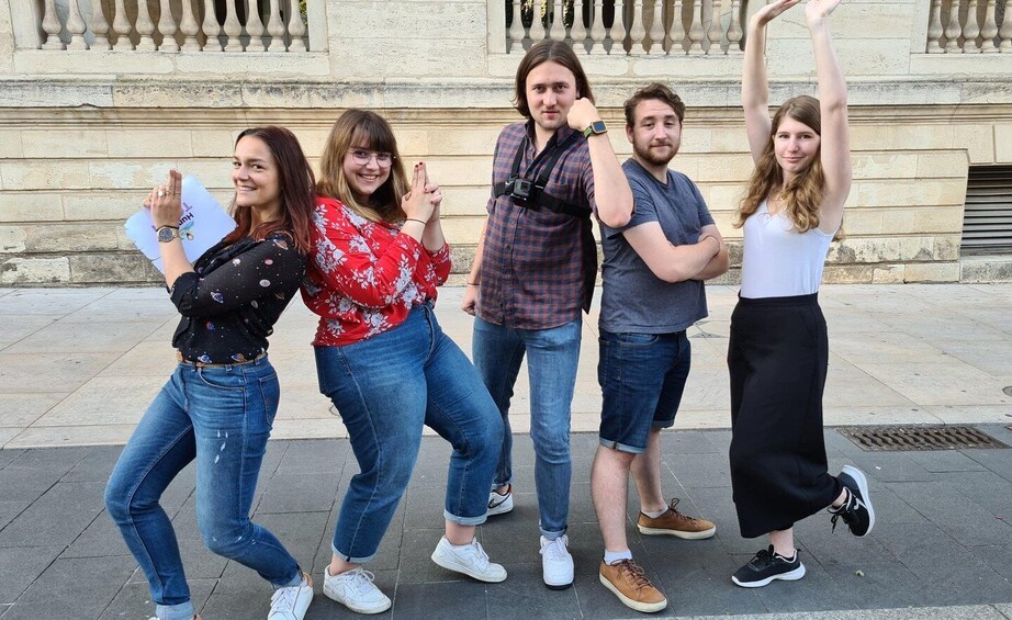 A group of people posing in front of a building with classical architecture. 1