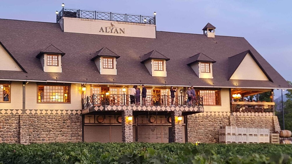 A building with the name 'ALYAN' on the roof, stone walls, and a balcony with people. 3