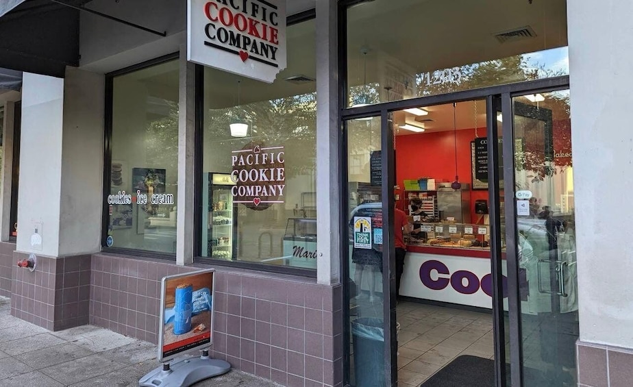 A Pacific Cookie Company storefront with a large window and a sign above the door. 1