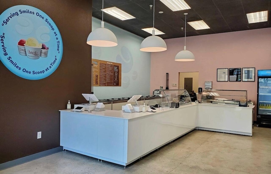 A modern ice cream shop with a counter, pendant lights, and a menu board. 4