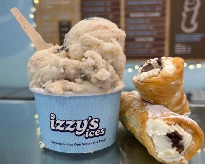 A cup of ice cream with a wooden stick and a pastry with a bite taken out of it. 5