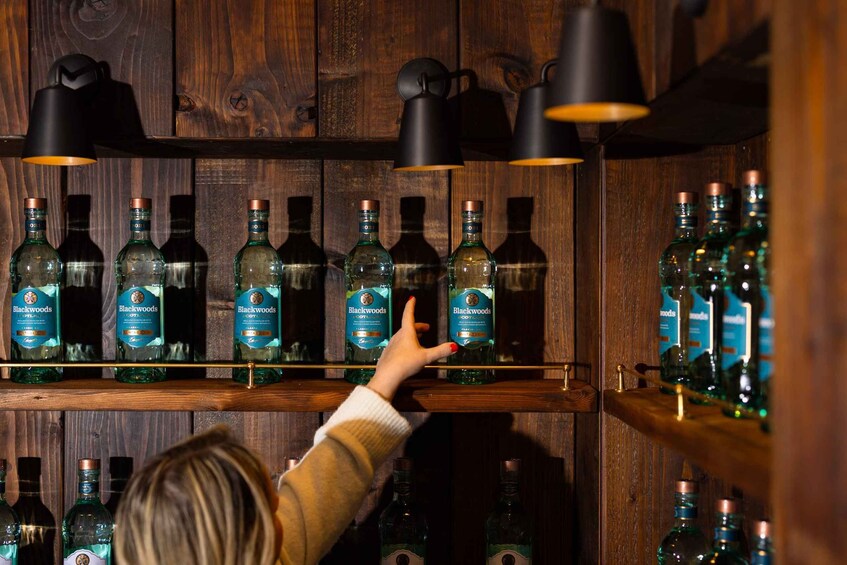 A person selecting a bottle from a shelf of Blackwoods whisky. 2