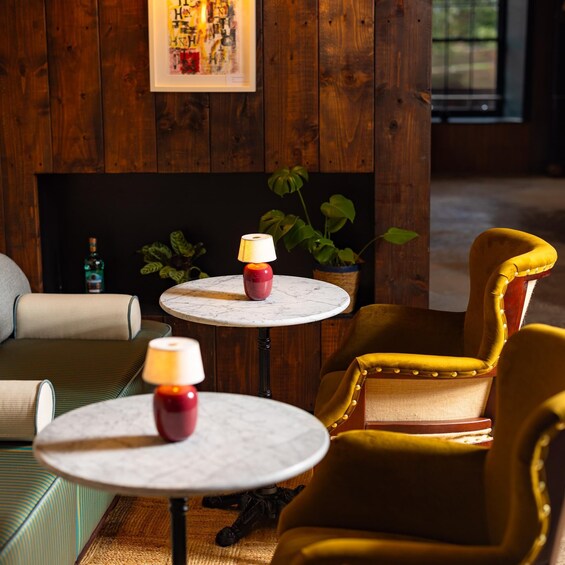 A cozy indoor setting with wooden walls, a fireplace, a yellow armchair, and two small tables with lamps. 5