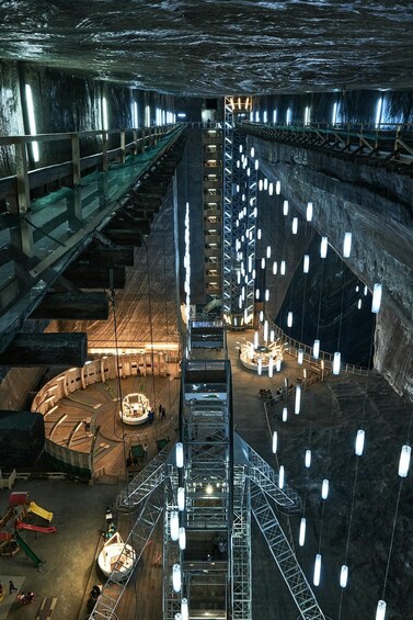 An underground construction site with a central staircase, metal scaffolding, and hanging lights. 5