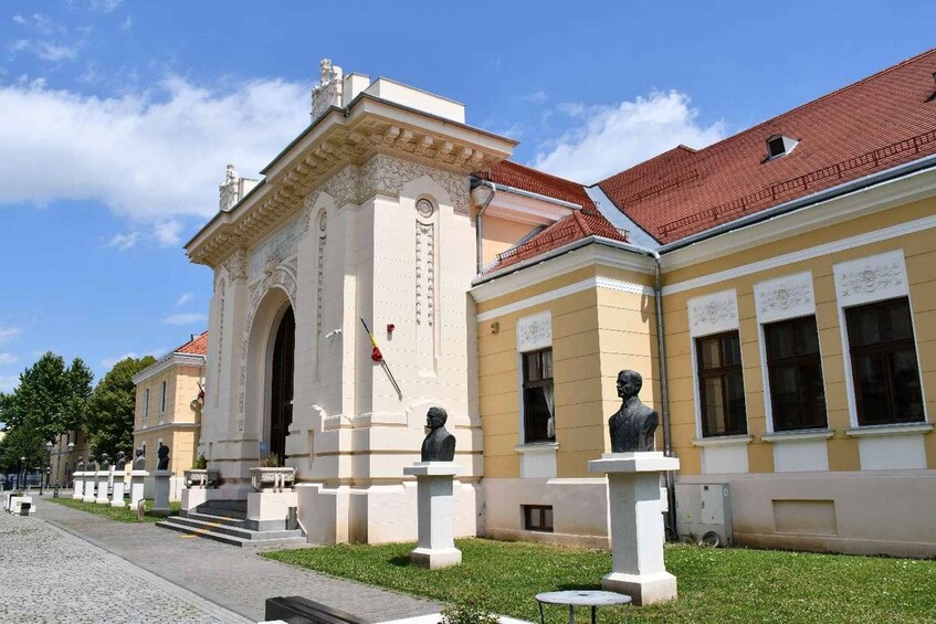 A classical building with statues, a cobblestone path, and a clear blue sky. 2