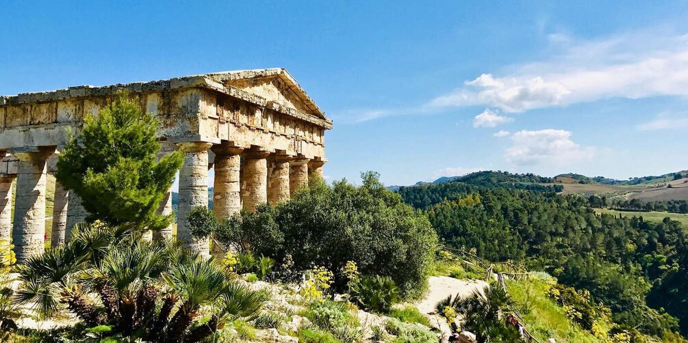 An ancient Greek temple with columns, surrounded by lush greenery and hills in the background. 3