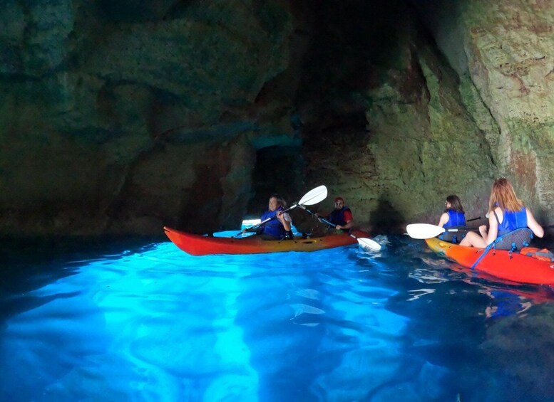 People kayaking in a cave with blue water. 5