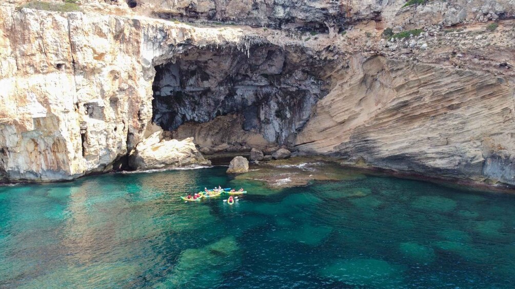 A group of kayakers navigating a narrow, rocky waterway surrounded by steep cliffs. 4