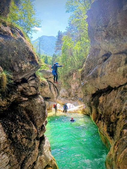 A canyon with a river, rocky cliffs, and a person rappelling down. 4