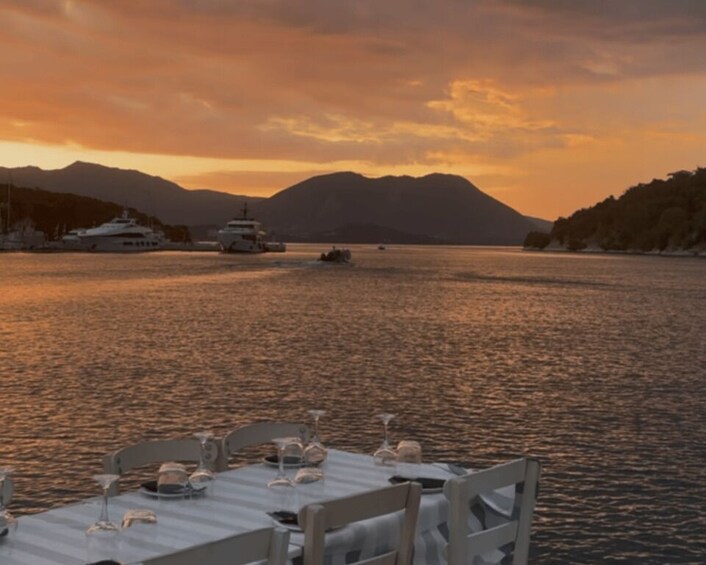 A table set for dinner with a view of a calm body of water, boats, and mountains in the background. 2