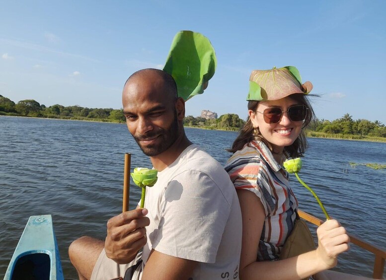 Two people on a boat holding paddles, with a body of water and greenery in the background. 2
