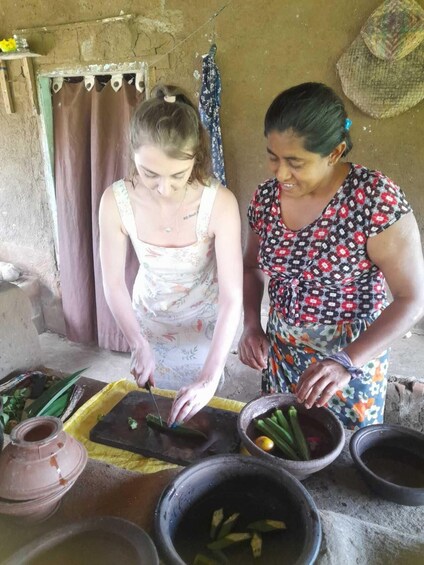 Two women preparing food outdoors with vegetables and cooking utensils. 4