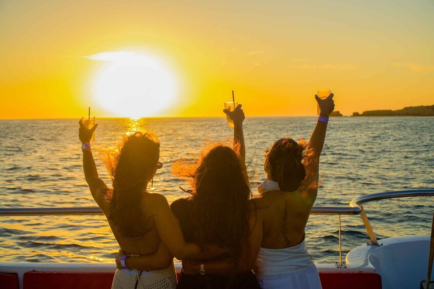 Three people on a boat at sunset with the sun low on the horizon. 2