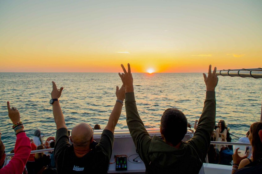 People on a boat at sunset with the sun setting on the horizon. 1
