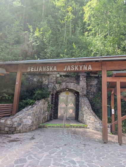 A wooden archway with the inscription 'BELIANSKA JASKYNA' above a stone entrance. 4