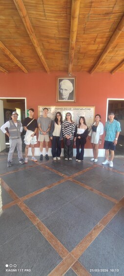 A group of people standing in a covered area with a tiled floor and a wooden ceiling. 4