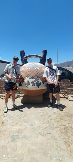 Two people standing beside a large, colorful sculpture with a face. 3
