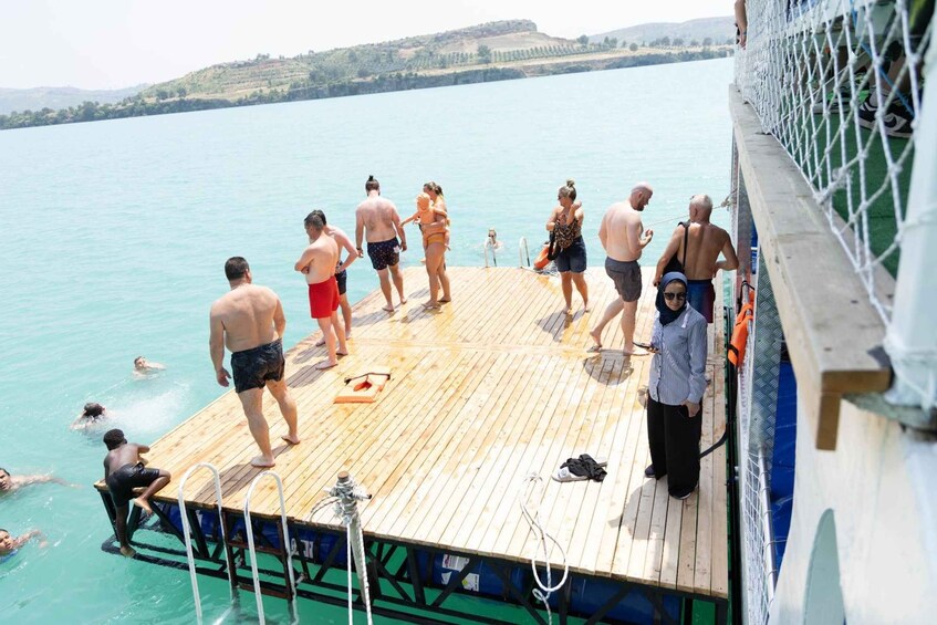 A wooden pier extending into a calm body of water with people swimming and standing on it. 2
