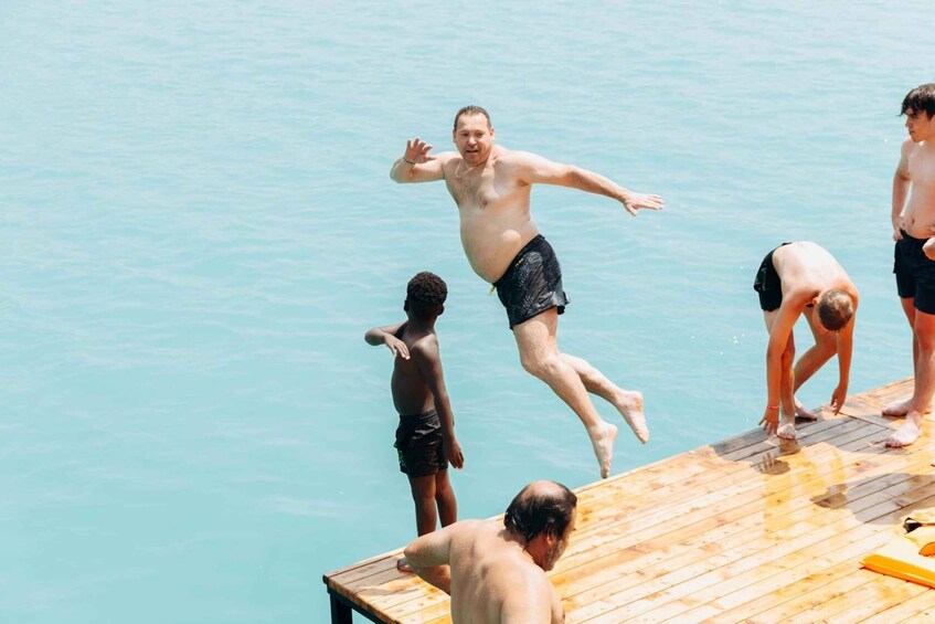 A wooden dock extending into a body of water with people engaging in water activities. 4