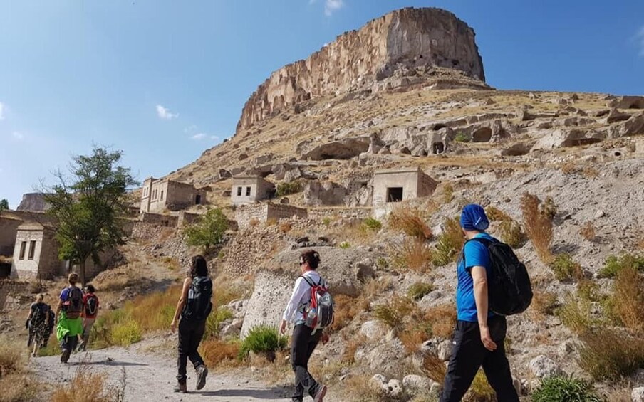 A group of hikers walking on a rocky path with a large rock formation in the background. 3