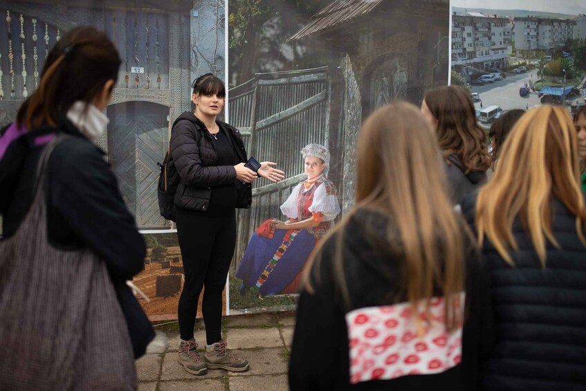 A person standing in front of a poster with a historical scene. 1