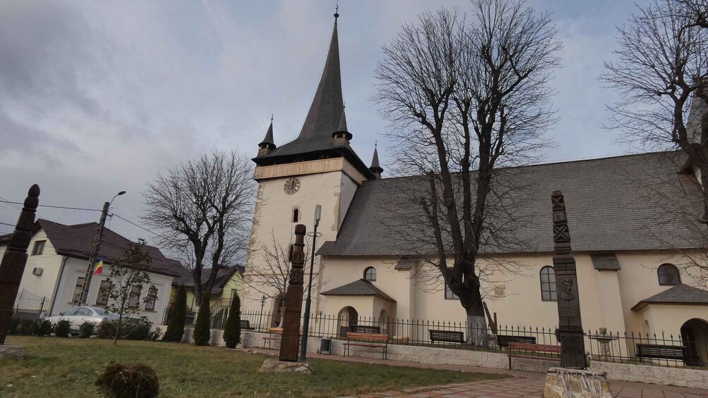 A church with a tall steeple and a clock, surrounded by bare trees and a paved walkway. 4