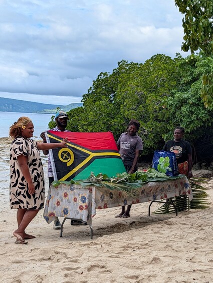 A beach scene with a table displaying a flag, vegetables, and a bag. 4
