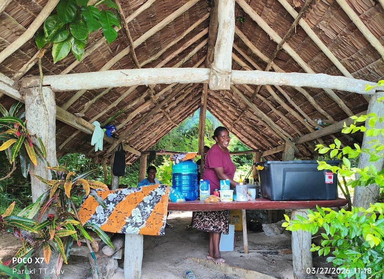 A rustic shelter with a thatched roof, a table with various items, and a television set. 3