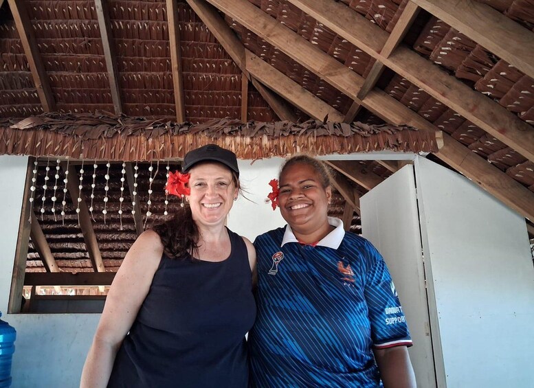 Two people standing under a wooden structure with a thatched roof. 3