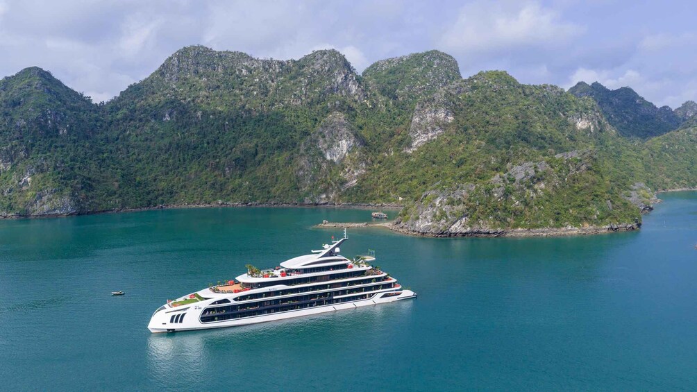 A cruise ship in a calm bay with lush green mountains in the background. 2