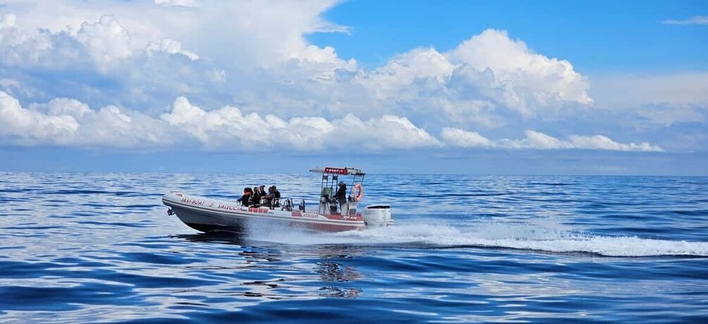 A speedboat with passengers on a calm sea under a partly cloudy sky. 1