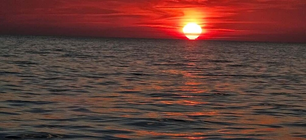 A sunset over the ocean with the sun partially visible above the horizon. 3