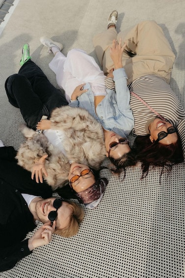 Four people lying on a patterned fabric surface outdoors. 5