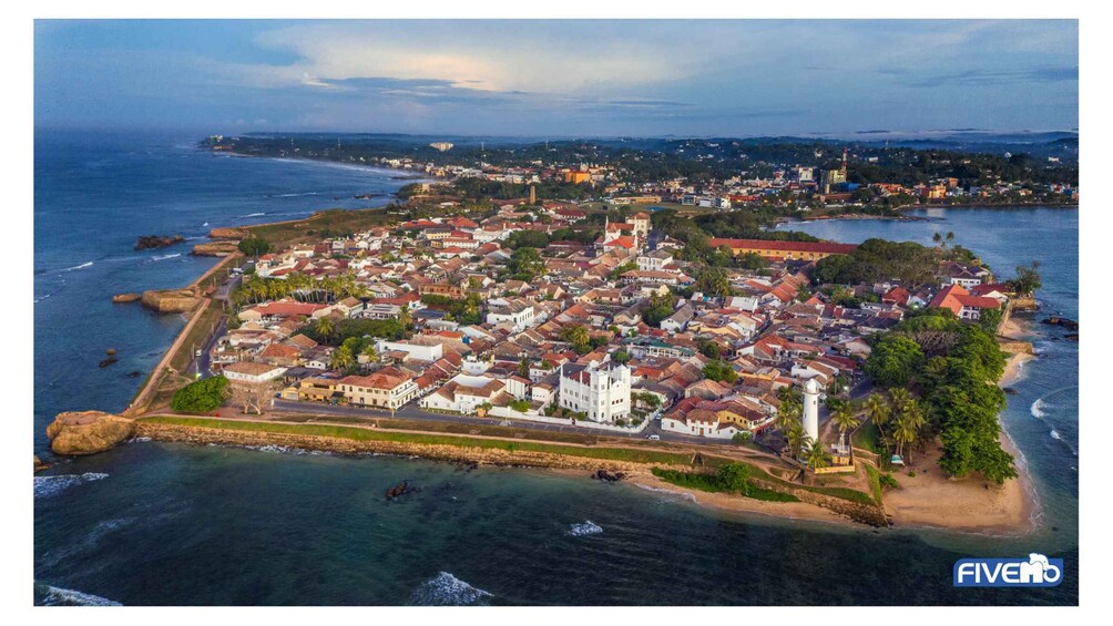 A coastal town with a prominent white church, a fort, and a mix of residential buildings. 2