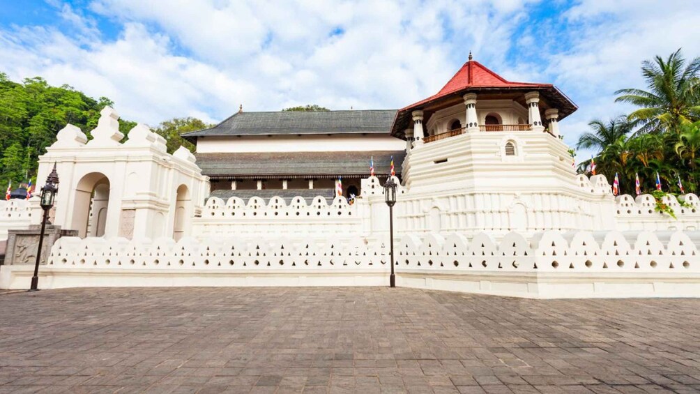 A traditional white building with a red roof, surrounded by a white wall with decorative elements. 4