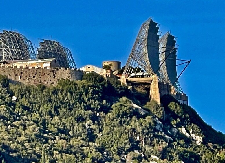A hillside with a large telescope structure and a building with scaffolding. 2