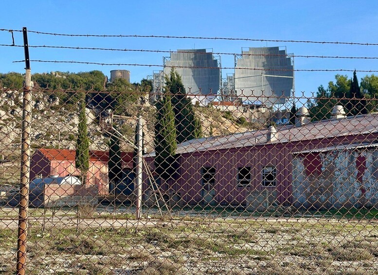A fenced industrial area with old buildings and cooling towers. 3