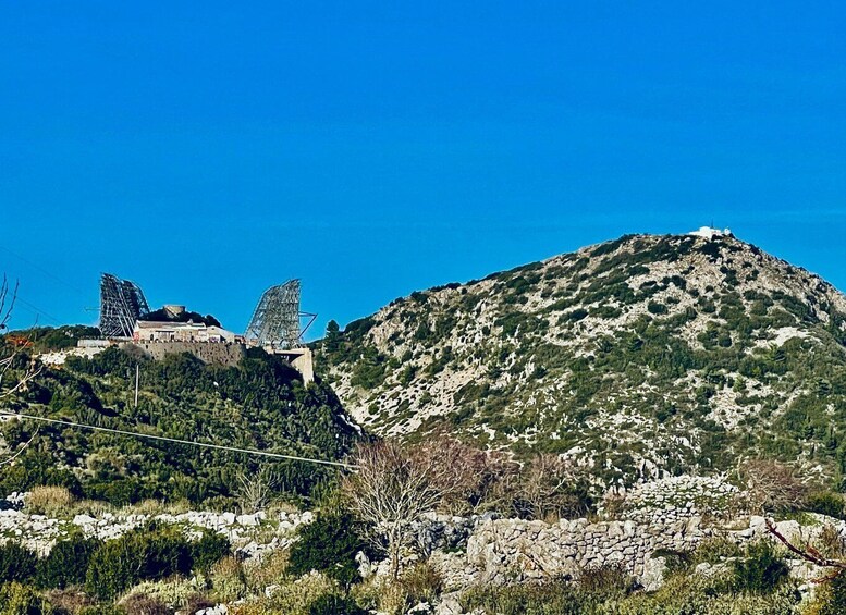 A mountainous landscape with a large rock formation and a structure with a metal framework. 5