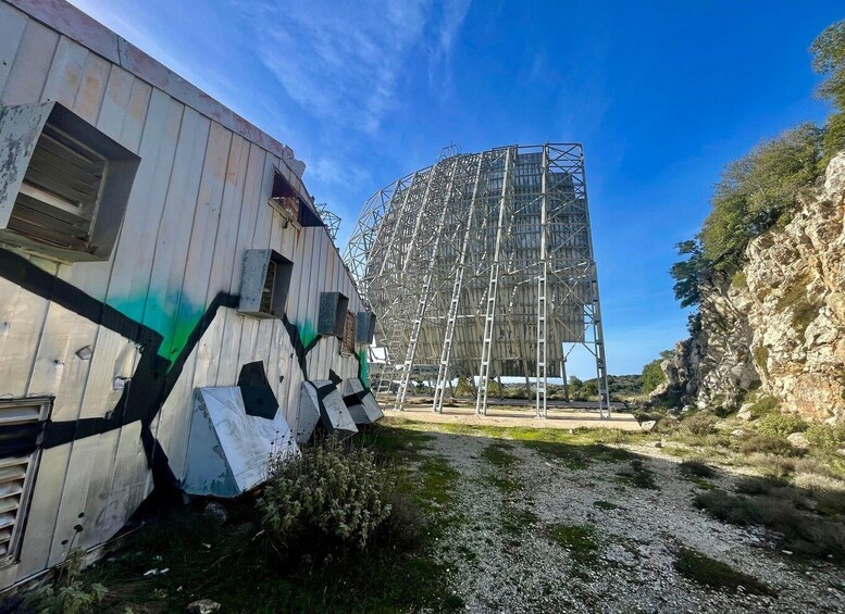 A dilapidated building with graffiti, a metal structure under construction, and a rocky landscape. 4