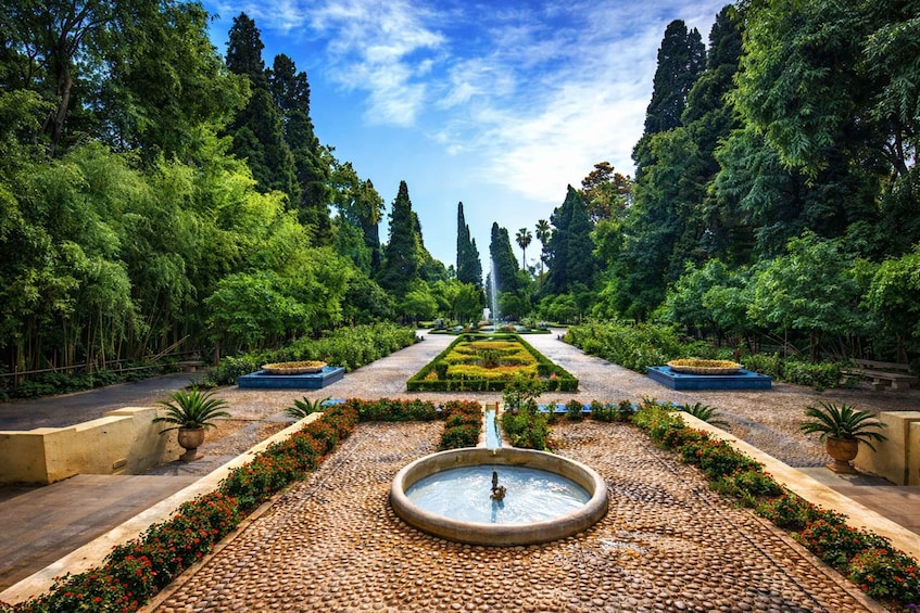 A formal garden with a central fountain, symmetrical pathways, and lush greenery. 1