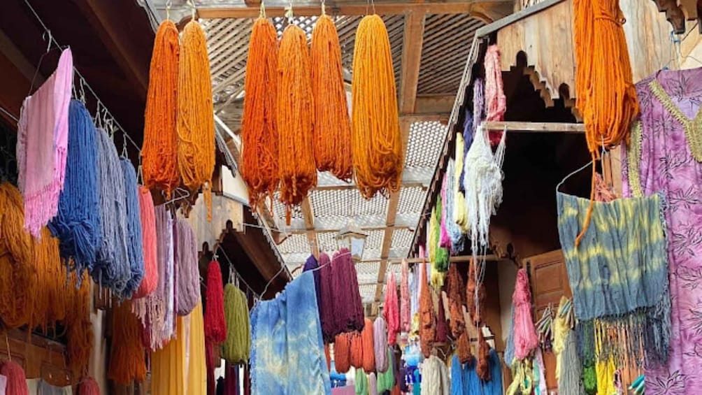 A market with colorful textiles hanging for sale. 3