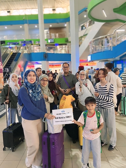 A group of people at an airport with luggage, a sign welcoming to Bintang, and an escalator in the background. 3
