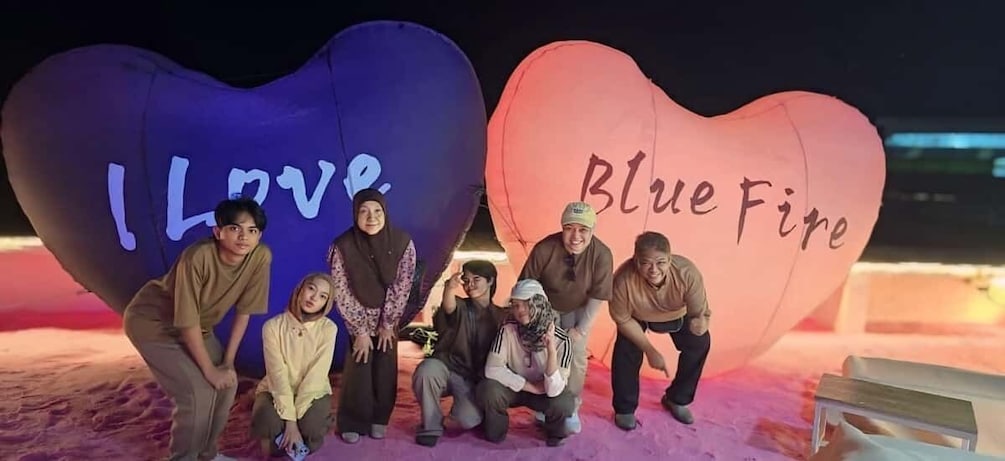 A group of people posing in front of heart-shaped balloons with 'I Love' and 'Blue Fire' written on them. 5