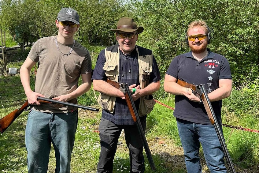 Three people holding shotguns in a wooded area. 5