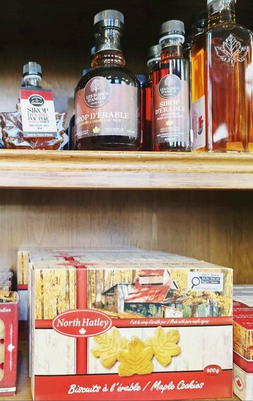 A shelf with maple syrup bottles and a box of North Hatley maple cookies. 5